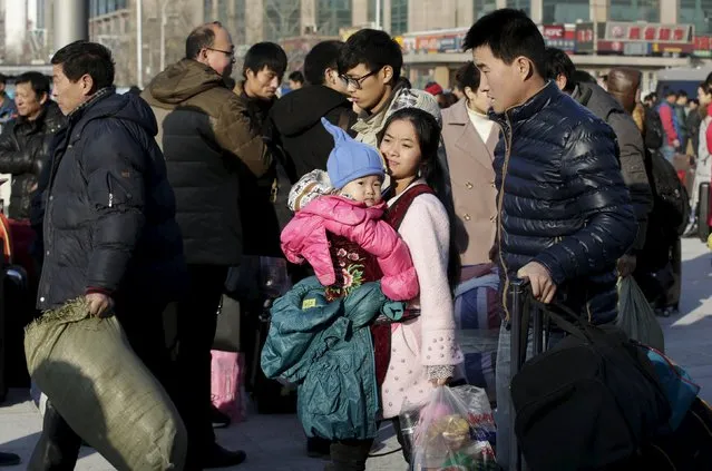 A mother carries her one-year-old daughter next to her husband (R) as the family arrive at Beijing Railway Station by train for Spring Festival, in Beijing, China, January 25, 2016. (Photo by Jason Lee/Reuters)
