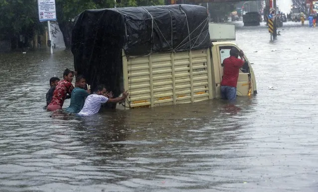 People push a mini pick up truck through a flooded street during heavy rains in Mumbai, India, Wednesday, June 9, 2021. (Photo by Rafiq Maqbool/AP Photo)
