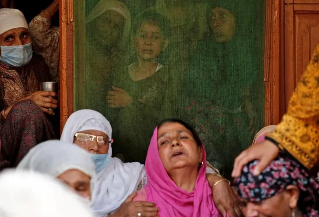 Women and a girl react as they wait for the body of Waseem Ahmad, an Indian policeman who according to local media was killed in a suspected militant attack in north Kashmir's Sopore town, at his house in Narbal on the outskirts of Srinagar on June 12, 2021. (Photo by Danish Ismail/Reuters)
