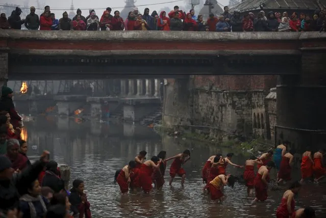 Devotees return after taking a holy bath at Bagmati River in Pashupatinath Temple during the Swasthani Brata Katha festival in Kathmandu, Nepal, February 8, 2016. (Photo by Navesh Chitrakar/Reuters)
