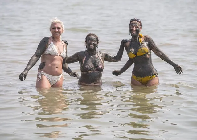 Three women cover themselves in mud while enjoying the hot weather at Southend beach, Essex in southeast England on Wednesday, July 21, 2021. (Photo by Ian West/PA Images via Getty Images)