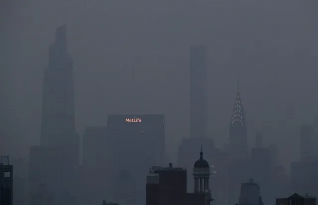 The Met Life and Chrysler buildings glow through a thick haze hanging over Manhattan, Tuesday, July 20, 2021, in New York. Wildfires in the American West, including one burning in Oregon that's currently the largest in the U.S., are creating hazy skies as far away as New York as the massive infernos spew smoke and ash into the air in columns up to six miles high. (Photo by Julie Jacobson/AP Photo)