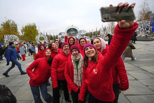 Volunteers make a selfie prior to perform during opening of the International exhibition “Russia” at VDNKh (The Exhibition of Achievements of National Economy) in Moscow, Russia, Saturday, November 4, 2023. The vast show was put together under a decree from President Vladimir Putin and is seen as encouraging patriotism in the runup to the presidential election in March. (Photo by Alexander Zemlianichenko/AP Photo)