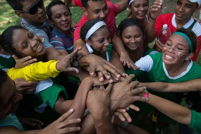 Female indigenous players of Satere Mawe tribe celebrate their victory of the final of Peladao, the amateur football tournament, in Manaus, Amazonas state, Brazil, on November 24, 2013. (Photo by Yasuyoshi Chiba/AFP Photo)