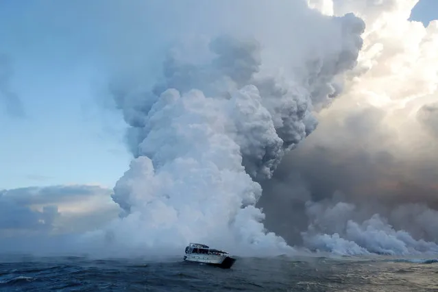 People watch from a tour boat as lava flows into the Pacific Ocean in the Kapoho area, east of Pahoa, during ongoing eruptions of the Kilauea Volcano in Hawaii, June 4, 2018. (Photo by Terray Sylvester/Reuters)