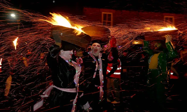 People parade through the streets with barrels of buring tar on New Year's Eve in Allendale, Britain, 31 December 2018. Dating back to 1858, 45 barrel carriers, called Guisers, parade through the town balancing whisky barrels filed with burning tar on their heads. The barrels are used to light a bonfire at midnight in the town center while spectators and participants shout “Bedamned to he who throws last”. (Photo by Nigel Roddis/EPA/EFE)