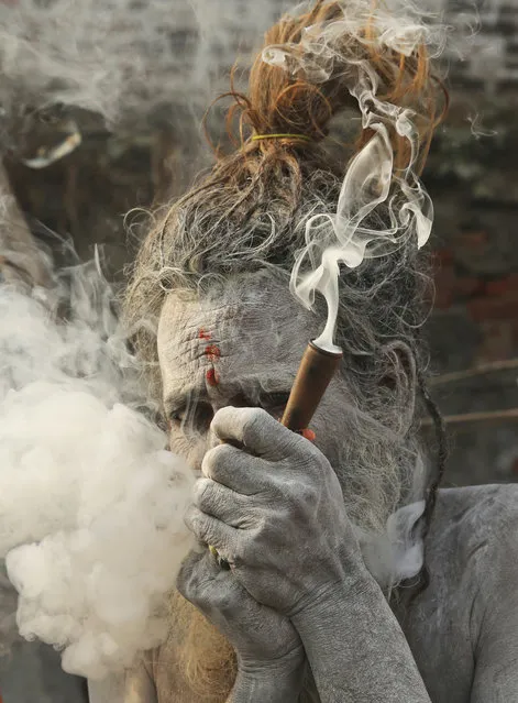 A Naga Sadhu, or a Hindu holy man, takes a smoke before participating in a procession towards the Sangam, the confluence of rivers Ganges and Yamuna, ahead of the Kumbh Mela in Allahabad, India, Thursday, January 3, 2019. Kumbh Mela is a 45-days festival beginning later this month, where millions of Hindu devotees are expected to attend with the belief that taking a dip in the holy waters will cleanse them of their sins. (Photo by Rajesh Kumar Singh/AP Photo)