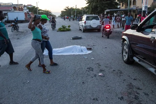 People walk past a body following a 7.2 magnitude earthquake in Les Cayes, Haiti on August 14, 2021. (Photo by Ralph Tedy/Reuters)