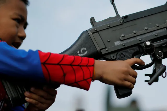 A child plays with a weapon on top of an army vehicle during Children's Day celebration at a military facility in Bangkok, Thailand January 14, 2017. (Photo by Jorge Silva/Reuters)