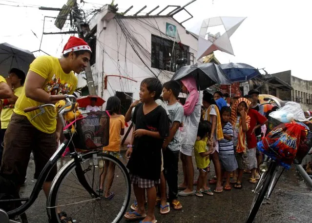 Children line up to receive a Christmas gift from volunteers in Tacloban, Philippines, Wednesday, December 25, 2013. Mostly, Christmas is a celebration amid deprivation, in tents, makeshift homes and damaged churches in the city devastated by the Nov. 8, typhoon Haiyan. (Photo by Achmad Ibrahim/AP Photo)