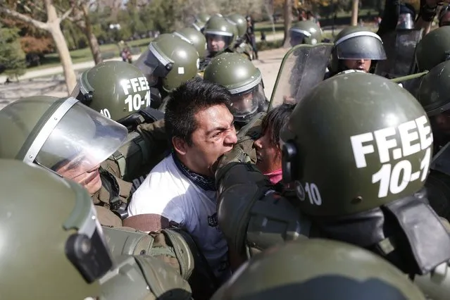 A student protester bites a riot policeman while being detained during a riot at a rally demanding Chile's government reform the education system in Santiago. (Photo by Ivan Alvarado/Reuters)