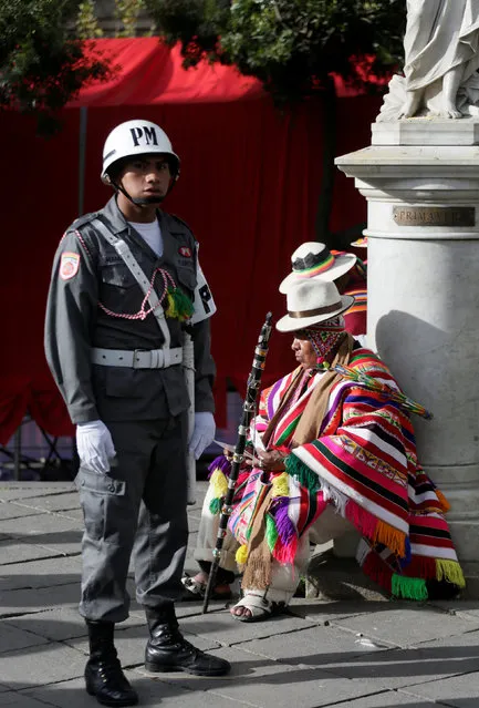 A soldier stands next to a witch doctor before a ceremony to mark 11 years of Bolivian President Evo Morales's administration at Murillo Square in La Paz, Bolivia, January 22, 2017. (Photo by David Mercado/Reuters)