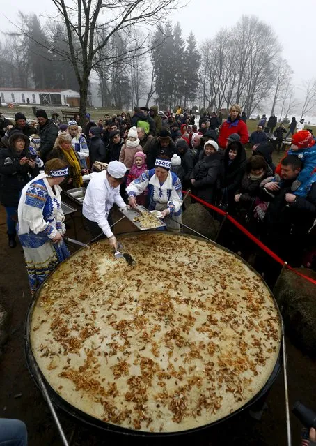 Employees cut fried dranik, a potato pancake that is the national dish of Belarus, to entertain visitors in the Sula History Park near the village of Sula, Belarus March 7, 2016. (Photo by Vasily Fedosenko/Reuters)