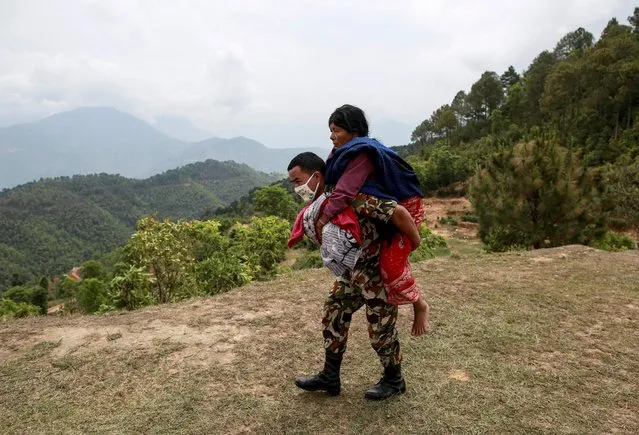 A Nepal Army personnel carries an injured woman to a helicopter following Saturday's earthquake in Sindhupalchowk, Nepal, April 28, 2015. (Photo by Danish Siddiqui/Reuters)