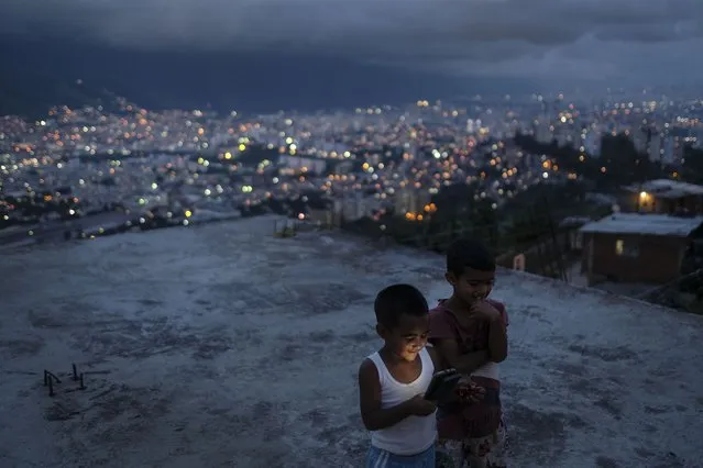Children play with their cellphone on the roof of a home in the El Quilombo neighborhood of Caracas, Venezuela, Thursday, September 23, 2021. (Photo by Matias Delacroix/AP Photo)