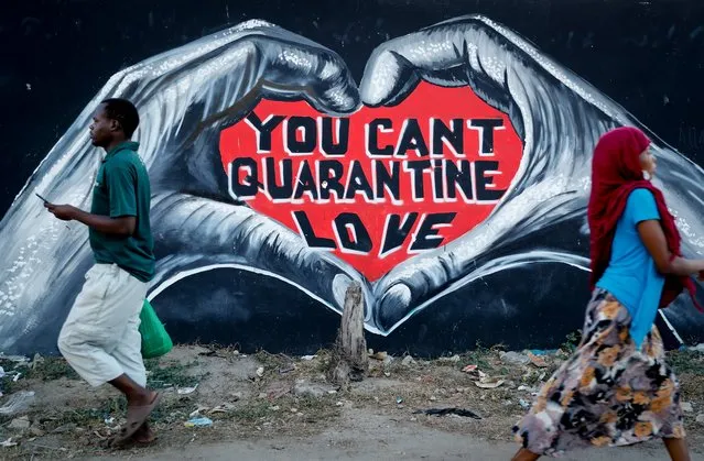 Pedestrians walk past a coronavirus information mural on a street in Mombasa, Kenya Monday, September 27, 2021. (Photo by Brian Inganga/AP Photo)