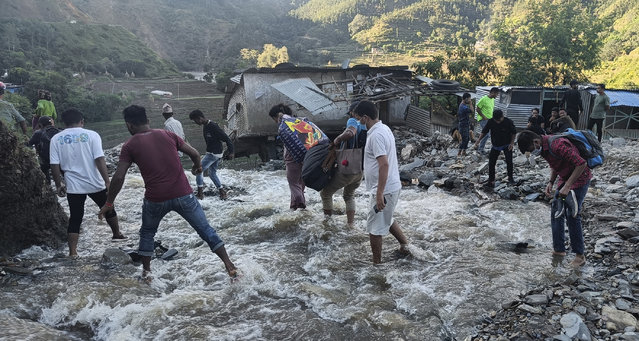 People wade past a flooded area in Dipayal Silgadhi, Nepal, Thursday, October 21, 2021. Floods and landslides triggered by days of torrential rains have killed at least 99 people in Nepal since Monday, officials said. (Photo by Laxmi Prasad Ngakhusi/AP Photo)
