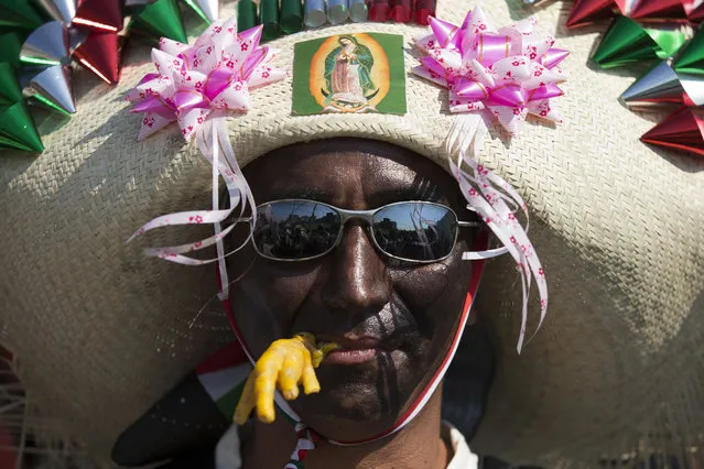 A man dressed as a Zacapoaxtla Indian, carrying a fake chicken's foot in his mouth, marches in a parade as residents prepare to reenact the battle of Puebla, between Zacapoaxtla Indians and the French army, during Cinco de Mayo celebrations in Mexico City, Tuesday, May 5, 2015. (Photo by Rebecca Blackwell/AP Photo)