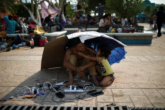 A migrant from Honduras watch other migrants' cellphones as they gather in an improvised shelter during a break in their journey towards the United States, in Escuintla, Mexico on April 19, 2019. (Photo by Jose Cabezas/Reuters)