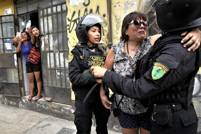 Police confort a neighbor who was harassed by anti-government protesters outside the San Marcos University in Lima, Peru, Saturday, January 21, 2023. Police evicted from the university grounds protesters who arrived from Andean regions seeking the resignation of President Dina Boluarte, the release from prison of ousted President Pedro Castillo and immediate elections. (Photo by Martin Mejia/AP Photo)
