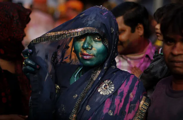 An Indian Hindu woman, drenched in colored water, looks on at the Nandagram Temple famous for Lord Krishna during Lathmar Holi festival in Nandgaon 120 kilometers ( 75 miles) from New Delhi, India, Monday, March 10, 2014. According to tradition which has its roots in Hindu mythology men from Barsana arrive at the temple where they are soaked in colored water by men from Nandgaon, believed to be Lord Krishna's village, and then beaten by the women of the village with wooden sticks as they depart the town. (Photo by Altaf Qadri/AP Photo)