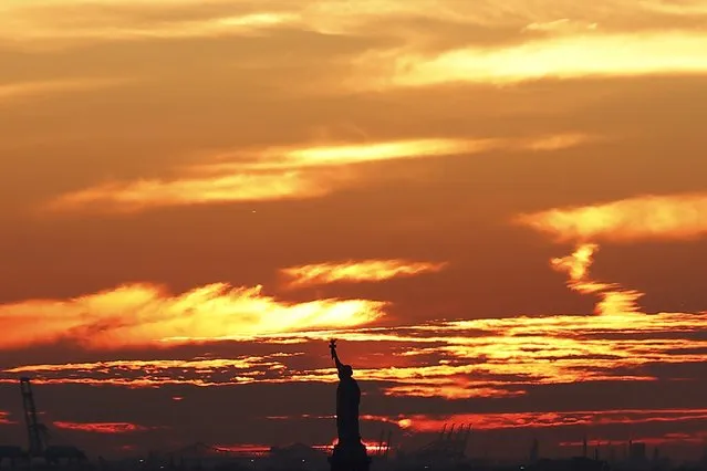 The sun sets behind the Statue of Liberty in New York Harbor with New Jersey behind, as seen from the Brooklyn Bridge in New York January 28, 2016. (Photo by Brendan McDermid/Reuters)