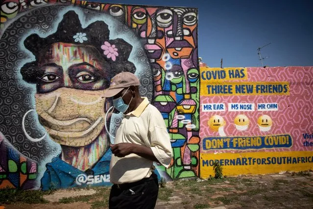 A Soweto resident walks in front of an informative graffiti art work educating local Soweto residents about the dangers of the coronavirus, Johannesburg, South Africa, 30 November 2021. South Africa's government is considering mandatory vaccinations for all citizens as it tries to educate and vaccinated its population after the new Omicron variant of SARS-CoV-2, the virus that causes COVID-19, was detected. Several countries banned travel with Southern African countries including South Africa due to the Omicron variant. (Photo by Kim Ludbrook/EPA/EFE)