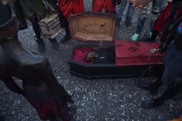 A fire- swallower around a coffin while perform in the third and final day of Carnival in the capital of Haiti, Port- au- Prince, on February 28, 2017. (Photo by Hector Retamal/AFP Photo)