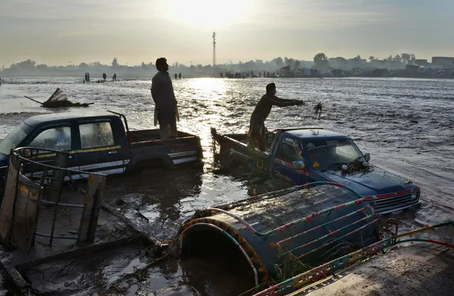 Pakistani men stand over their vehicles submerged by flood water following heavy rain on the outskirts of Peshawar on April 4, 2016. (Photo by A. Majeed/AFP Photo)