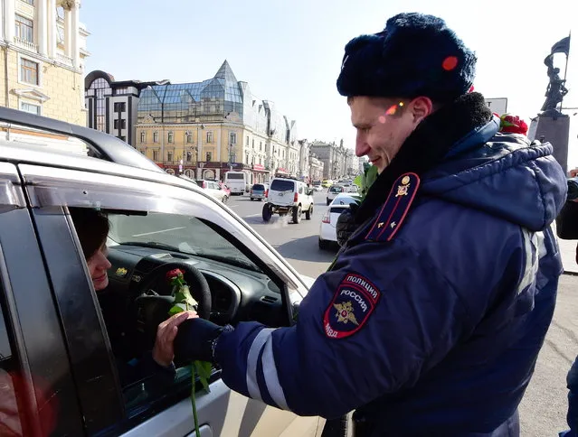 A traffic policeman congratulates a female driver on upcoming International Women's Day in the citys Central Square in Vladivostok, Russia on March 7, 2017. (Photo by Yuri Smityuk/TASS via Getty Images)