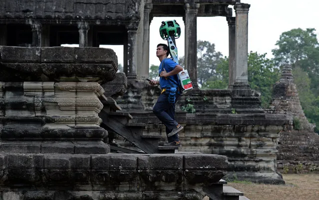 A Cambodian technician carries a back-pack mounted with a device housing 15 cameras as he demonstrates the technique used to digitally map the Angkor Wat temple, part of the Angkor architectural complex in north-western Cambodia on April 3, 2014. Cambodia's Angkor Wat has been digitally mapped for the first time, allowing people to visit the famed temples from the comfort of their armchair using Google Street View. (Photo by Christophe Archambault/AFP Photo)