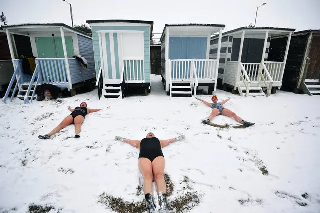 Essex swimmers, from left, Sallyann Manthorp, Peta Hunter and Victoria Carlin make angels in the snow as bitterly cold winds continue to grip much of the nation, at Thorpe Bay, Essex, England, Tuesday, February 9, 2021. (Photo by Victoria Jones/PA Wire via AP Photo)