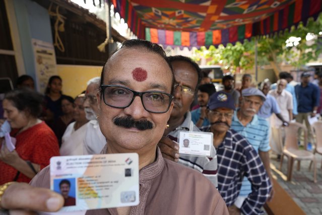 A man shows his voter's identity card as he queues up with others to vote during the second round of voting in the six-week-long national election near Palakkad, in Indian southern state of Kerala, Friday, April 26, 2024. (Photo by Manish Swarup/AP Photo)