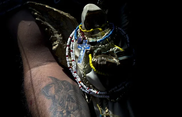 In this March 1, 2017 photo, a devotee of the Death Saint or “Santa Muerte”, who has a tattoo of the folk saint, holds his statuette during a pilgrimage in Mexico City's Tepito neighborhood. When Pope Francis visited Mexico last year he expressed concern for those who “praise illusions and embrace their macabre symbols to commercialize death in exchange for money”. (Photo by Marco Ugarte/AP Photo)