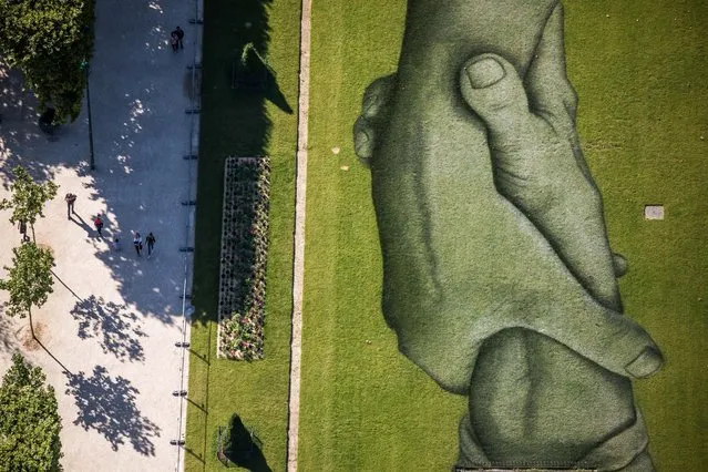 An upper view taken from the Eiffel Tower shows a part of the giant landart painting of the project entitled “Beyond Walls” by French artist Saype in the Champs-de-Mars garden in Paris, France, 14 June 2019. The 600-meter long fresco will be inaugurated from the Eiffel Tower on 15 June in support of the association of sea rescue SOS Mediterranee. His work is inspired by the hand extended by the lifeguards to assist the refugees in distress in the Mediterranean. (Photo by Christophe Petit Tesson/EPA/EFE/Rex Features/Shutterstock)
