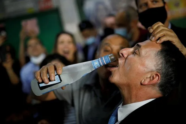 A man pours alcoholic drink into the mouth of New Hope party leader Gideon Saar as he campaigns ahead of the March 23 general election, at a market in Tel Aviv, Israel on March 17, 2021. (Photo by Amir Cohen/Reuters)