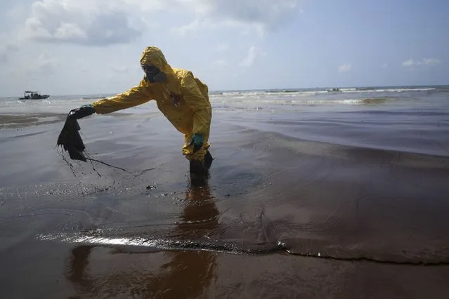 Workers carry out a clean-up operation on Mae Ramphueng Beach after a pipeline oil spill off the coast of Rayong province in eastern Thailand, Saturday, January 29, 2022. At least 20 tons of oil leaked Tuesday night from an undersea hose at an offshore mooring point of the Star Petroleum Refining Co. used to load tankers, and despite efforts to disperse or contain it, some reached the beach Saturday morning, while a large slick remains at sea. (Photo by Nava Sangthong/AP Photo)