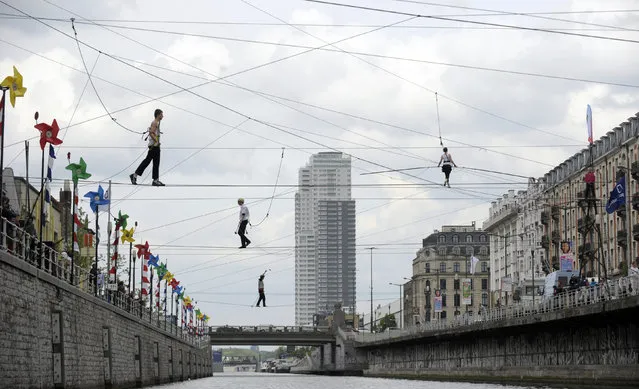 Tightrope walkers perform above a canal in Brussels April 26, 2014. Approximately forty-four tightrope walkers made an attempt to cross the canal during a performance. (Photo by Laurent Dubrule/Reuters)