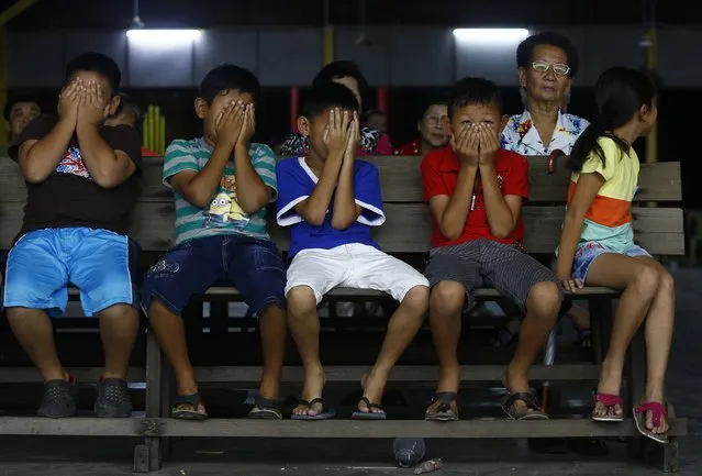 Children cover their faces as they watch a Chinese Opera performance in Pulau Ketam, outside Kuala Lumpur May 7, 2014. Picture taken May 7, 2014. (Photo by Samsul Said/Reuters)