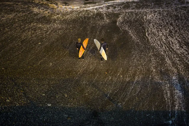 In this March 1, 2017 photo, surfers prepare to jump in the Pacific Ocean in La Pampilla beach in Lima, Peru. The Andean country has decked out Pampilla with four 1,000-watt lights like those used in soccer stadiums. Placed high above the beach, their lights reach about 200 meters out to the water, providing enough illumination to surf after nightfall. (Photo by Rodrigo Abd/AP Photo)