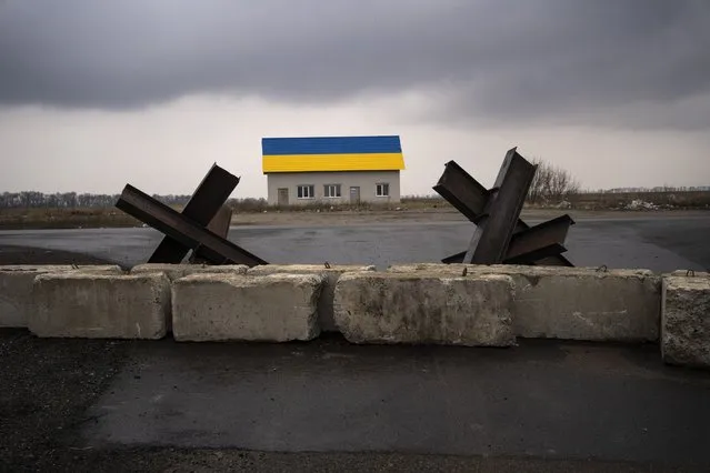 Anti-tank barriers are displayed near a house painted with the colors of the Ukraine flag near Malaya Alexandrovka village, on the outskirts of Kyiv, Ukraine, Wednesday, March 30, 2022. (Photo by Rodrigo Abd/AP Photo)