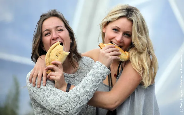 Cornish students (R) Nina Brooke, 21 and (L) Bonnie Mably, 20, laugh as they pose for a photograph as they try a Cornish pasty that has been baked as part of the World Cornish Pasty Championships at The Eden Project