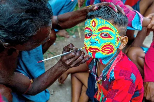 A village boy's face is painted colorfully by an artist as they attend and celebrate the Bengali New Year festival called Pahela Boisakh in Bardhaman District, West Bengal, India on April 11, 2022. Before the festival some villagers celebrate the Gajan festival associated with gods as Shiva, Neel, and Dharmathakur. This festival spans around a week, starting from the last week of Choitro and continuing till the end of the Bengali New Year. (Photo by Saurabh Sirohiya/ZUMA Press Wire/Alamy Live News)