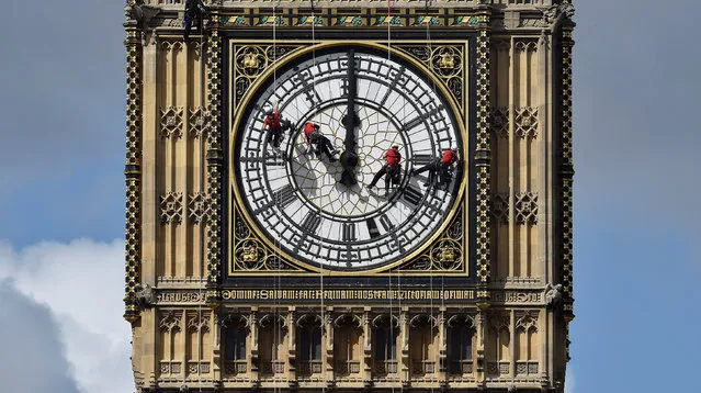 Cleaners abseil down one of the faces of Big Ben, to clean and polish the clock face, above the Houses of Parliament, in central London August 19, 2014. (Photo by Toby Melville/Reuters)