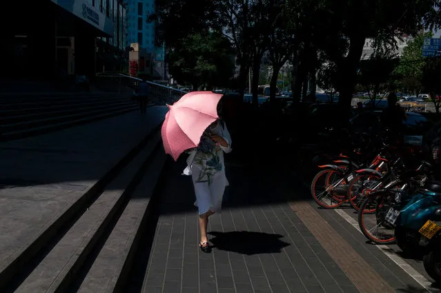 A pedestrian uses her umbrella to protect against the sun in Beijing on May 26, 2017. Moody' s on May 24 slashed China' s credit rating for the first time in almost three decades citing concerns about the country' s rising debt and slowing growth, but Beijing rejected the downgrade as “inappropriate”. (Photo by Fred Dufour/AFP Photo)