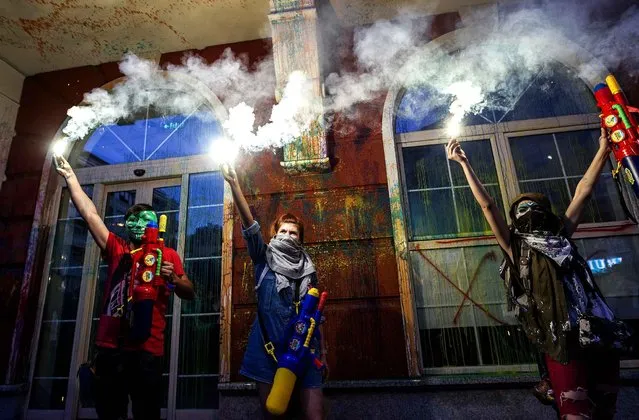 Protesters light flares after they spray paint on the facade of the Ministry of Justice building, during an anti-government protest in Skopje on May 31, 2016, in a series of protests dubbed Colorful Revolution. Macedonia's president revoked on May 27 the pardons he had granted to 22 politicians implicated in a wiretapping scandal, after the move sparked outrage inside and outside the troubled Balkan country. (Photo by Robert Atanasovski/AFP Photo)