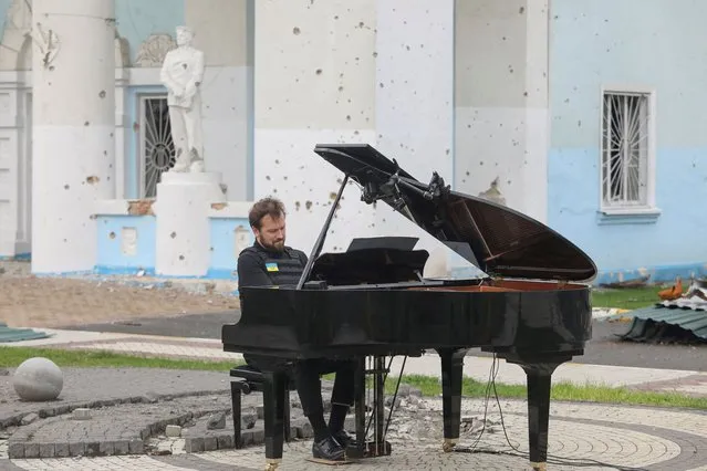 Lithuanian musician Darius Mazintas plays a piano in front of the Central House of Culture destroyed during Russia's invasion, in the town of Irpin, outside Kyiv, Ukraine on April 26, 2022. (Photo by Mykola Tymchenko/Reuters)