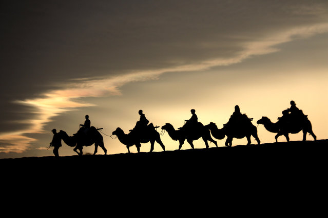 Camel-riding visitors enjoy the sights at the Mingsha Mountain and Crescent Spring scenic spot in the city of Dunhuang, northwest China's Gansu Province, on September 1, 2024. (Photo by Zhang Xiaoliang/Xinhua News Agency)