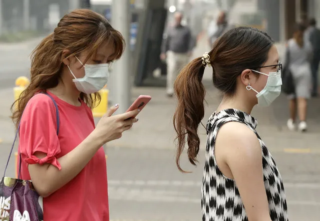 In this January 2, 2020, file photo, pedestrians wear masks as smoke shrouds the Australian capital of Canberra, Australia. It's an unprecedented dilemma for Australians accustomed to blue skies and sunny days that has raised fears for the long-term health consequences if prolonged exposure to choking smoke becomes the new summer norm. (Photo by Mark Baker/AP Photo/File)