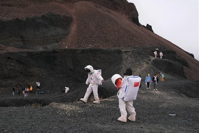 People dressed in astronaut costumes pose for pictures while visiting the Volcano No. 6 of the Ulan Hada volcano group near Ulanqab, Inner Mongolia Autonomous Region, China October 4, 2021. (Photo by Carlos Garcia Rawlins/Reuters)